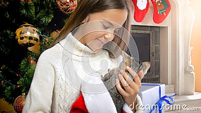 Portrait of beautiful teenage girl with kitten sitting under decorated Christmas tree Stock Photo