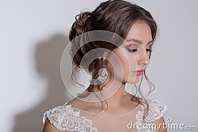 Portrait of a beautiful tender young bride with evening festive hair and gentle make-up in a snow-white dress with a train Stock Photo