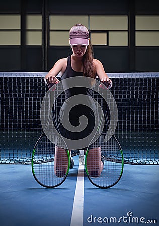 Portrait of a beautiful tennis player posing with two rackets on the court. Sports concept Stock Photo