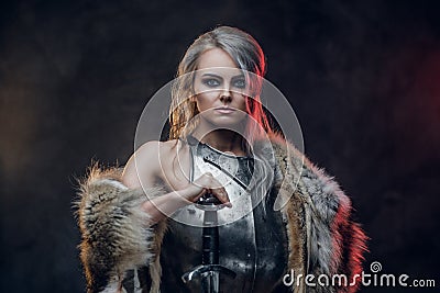 Portrait of a beautiful warrior woman holding a sword wearing steel cuirass and fur. Fantasy fashion. Cosplayer as Ciri Stock Photo