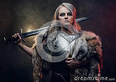 Portrait of a beautiful warrior woman holding a sword wearing steel cuirass and fur. Fantasy fashion. Cosplayer as Ciri Stock Photo