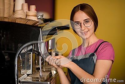 portrait of beautiful woman barista stands at coffee machine and prepares drink Stock Photo