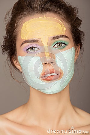 beautiful woman with colorful cream mask on her face Stock Photo
