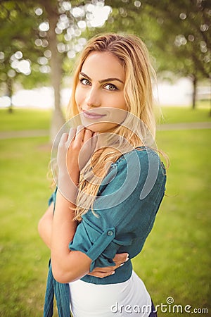 Portrait of beautiful woman with hand on chin while standing on grass Stock Photo