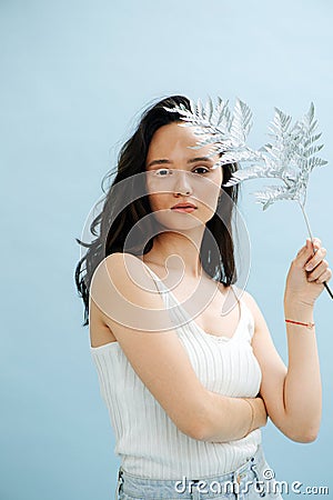 Portrait of beautiful woman holding white fern near face and vitiligo eyelashes Stock Photo