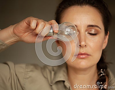 Woman holds incandescent light bulb in front of her Stock Photo