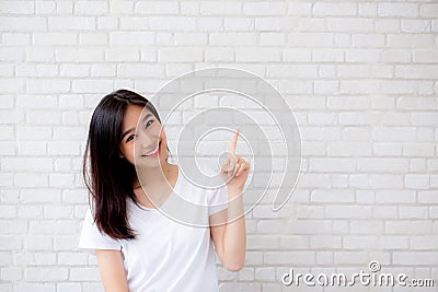 Portrait of beautiful young asian woman happiness standing finger pointing something on gray cement texture Stock Photo