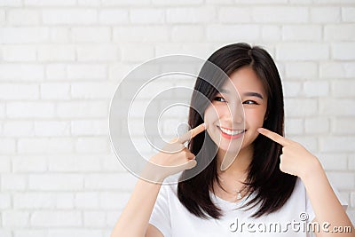 Portrait of beautiful young asian woman happiness standing finger touch cheek on gray cement texture grunge wall brick background Stock Photo