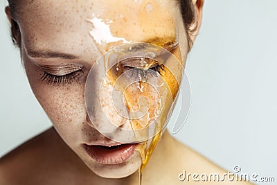 Portrait of beautiful young brunette woman with freckles and honey on face with closed eyes and serious face, head down Stock Photo