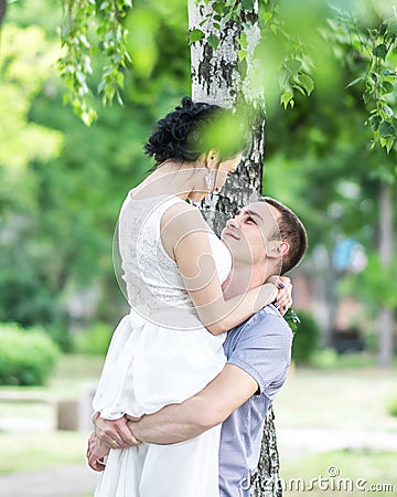 Portrait of beautiful young couple female bride and male bridegroom hugging and looking at each other in summer park. Man husband Stock Photo