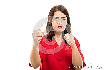 Portrait of beautiful young doctor wearing scrubs showing fists Stock Photo