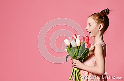 Portrait of a beautiful young girl in dress holding big bouquet of irises and tulips isolated over pink background Stock Photo