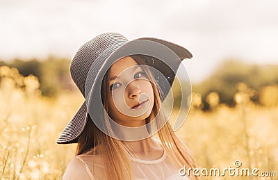 Portrait of a beautiful young girl in a hat against the background of a rapeseed field Stock Photo
