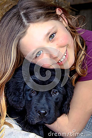 Portrait of a beautiful young girl and her newfoundland puppy hugging Stock Photo