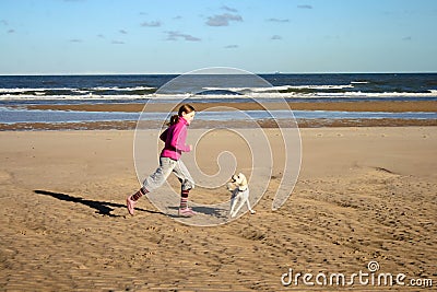 Portrait of a beautiful young girl and her puppy running on the beach Stock Photo