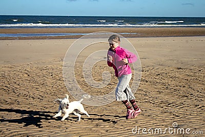 Portrait of a beautiful young girl and her puppy running on the beach Stock Photo