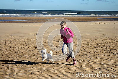 Portrait of a beautiful young girl and her puppy running on the beach Stock Photo