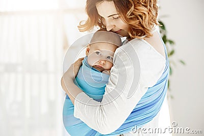 Portrait of beautiful young mother holding tight her newborn baby boy with love and caring. She smiling and feeling Stock Photo