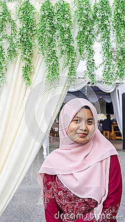 A portrait of beautiful young Muslim Malay woman wearing a hijab and dress called `Baju Kurung` Stock Photo