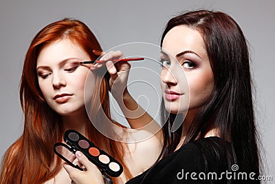 Portrait of beautiful young redheaded woman with esthetician making makeup Stock Photo