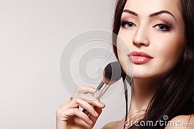 Portrait of beautiful young redheaded woman with makeup brush Stock Photo