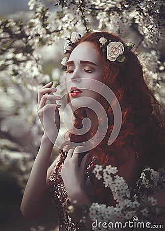 Portrait of a beautiful young sensual woman with very long red curly hair in spring flowers. Colors of spring . Stock Photo