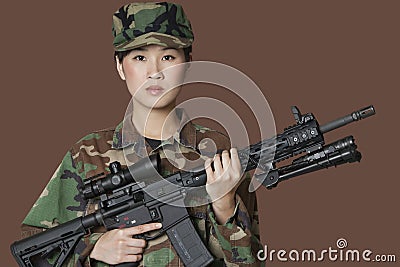 Portrait of beautiful young US Marine Corps soldier with M4 assault rifle over brown background Stock Photo