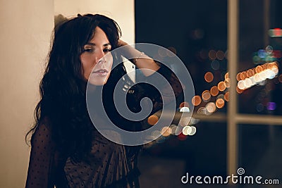 Portrait of beautiful young woman in black cocktail dress leaning on wall Stock Photo