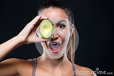 Beautiful young woman holding avocado over black background. Stock Photo