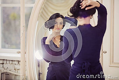 Beautiful young woman looking in mirror indoors Stock Photo