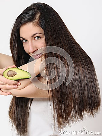 Portrait of a beautiful young woman posing with an avocado over white isolated background Stock Photo