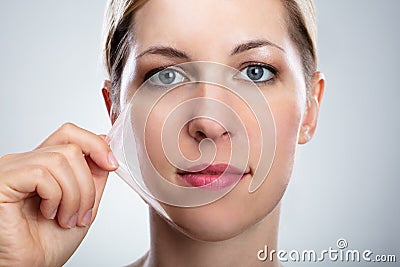 Woman Removing Peeling Mask From Her Face Stock Photo