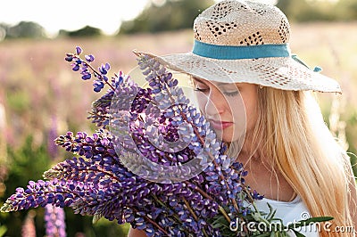 Portrait of a beautiful young woman in a straw hat with a bouquet of plucked lupins Stock Photo
