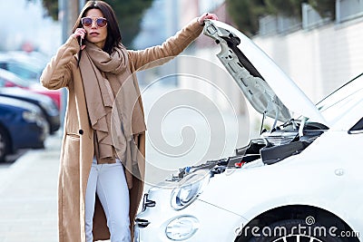 Beautiful young woman using her mobile phone calls for assistance for car. Stock Photo