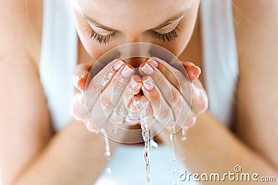Beautiful young woman washing her face splashing water in a home bathroom. Stock Photo