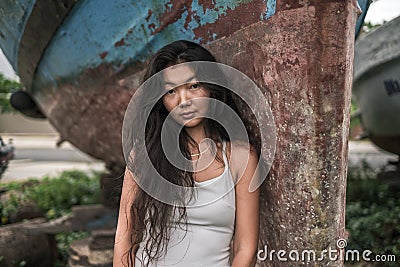 Portrait of beautiful young woman in white dress standing near the old ship Stock Photo