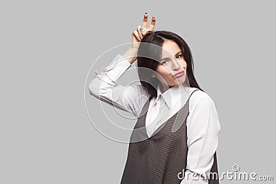 Portrait of beautiful young woman in white shirt and brown apron with makeup and brunette hair standing doing funny face and Stock Photo