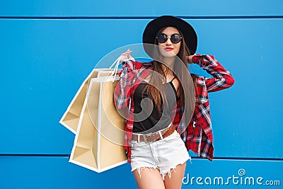 Portrait of beauty fashion smiling woman with shopping bags in sunglasses on blue background. Outdoor. Copyspace Stock Photo