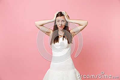 Portrait of bewildered puzzled bride woman in lace white wedding dress worries clinging to head standing isolated on Stock Photo