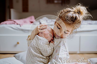 Portrait of big sister holding newborn sister. Girl carefully cuddling small baby. Sisterly love, joy for new family Stock Photo