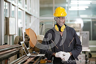Portrait of black male african american workers wear sound proof headphones and yellow helmet standing an iron cutting machine. Stock Photo