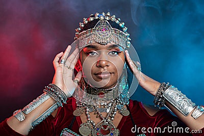 Portrait of a black-skinned teenager in festive oriental jewelry made of metal in the studio on a dark background Stock Photo