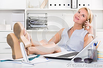 Portrait of blond adult girl in office talk on telephone Stock Photo