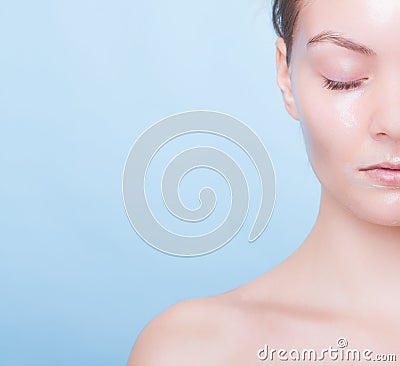 Portrait blond girl in facial mask on blue. Part face. Beauty and skin care. Stock Photo