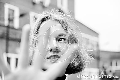 Portrait of blonde kinky girl looking through her fingers Stock Photo