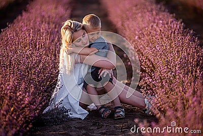 Portrait mother with little son are sitting in purple lavender field. Concept of allergy, travel Stock Photo