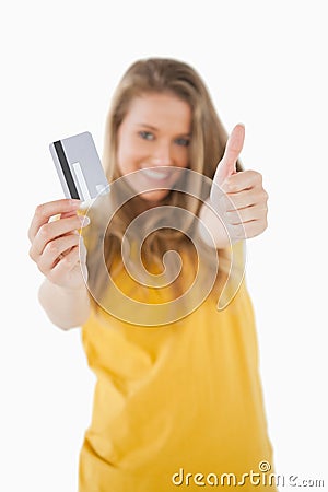 Portrait of a blonde student tending a credit card with the thumb-up Stock Photo