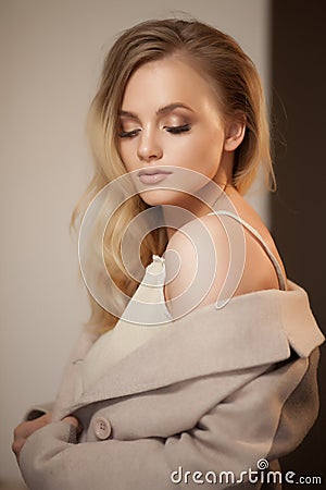 Portrait of a blonde woman wearing beige coat, looking over shoulder. Stock Photo