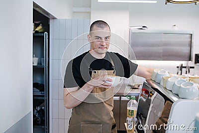 Portrait of a bold male baker posing with coffee cup in hands Stock Photo