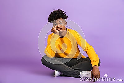 Portrait of bored african american boy sitting on floor with leg Stock Photo